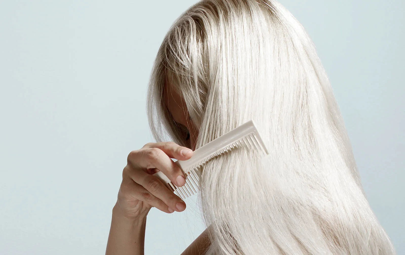 Hellblonde Frau, die ihre langen Haare kämmt